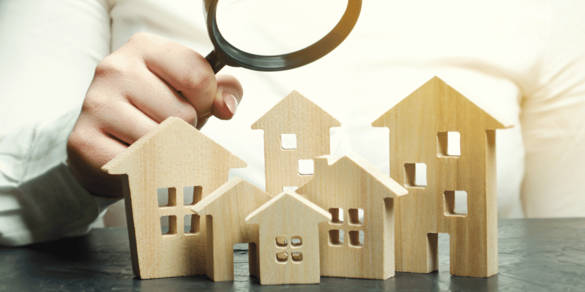 Small, wooden models of houses being examined with a magnifying glass